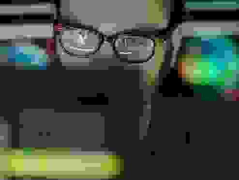 a guy with glasses looking at a laptop screen